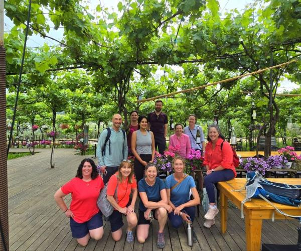 Multicultural group gathered under grapevines during the electric bike tour to Roshnik.