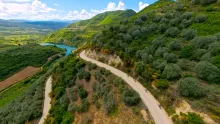 Group riding electric bikes through green hills and rural roads near Berat on the way to Roshnik.